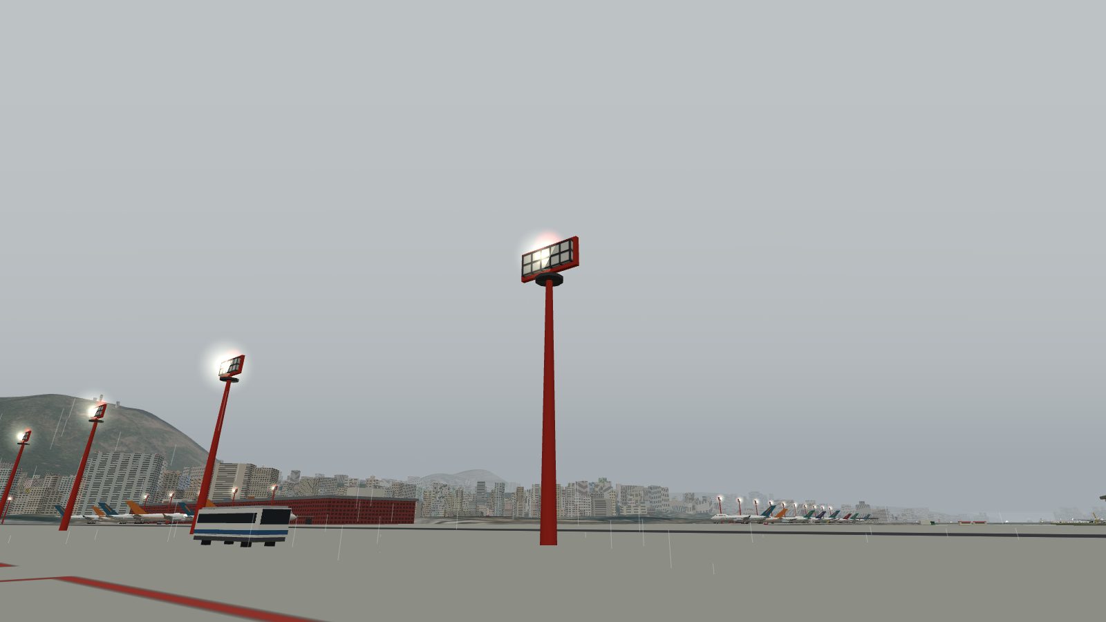 The same masts in rain under an overcast sky, their lamps and red obstruction lights lit.