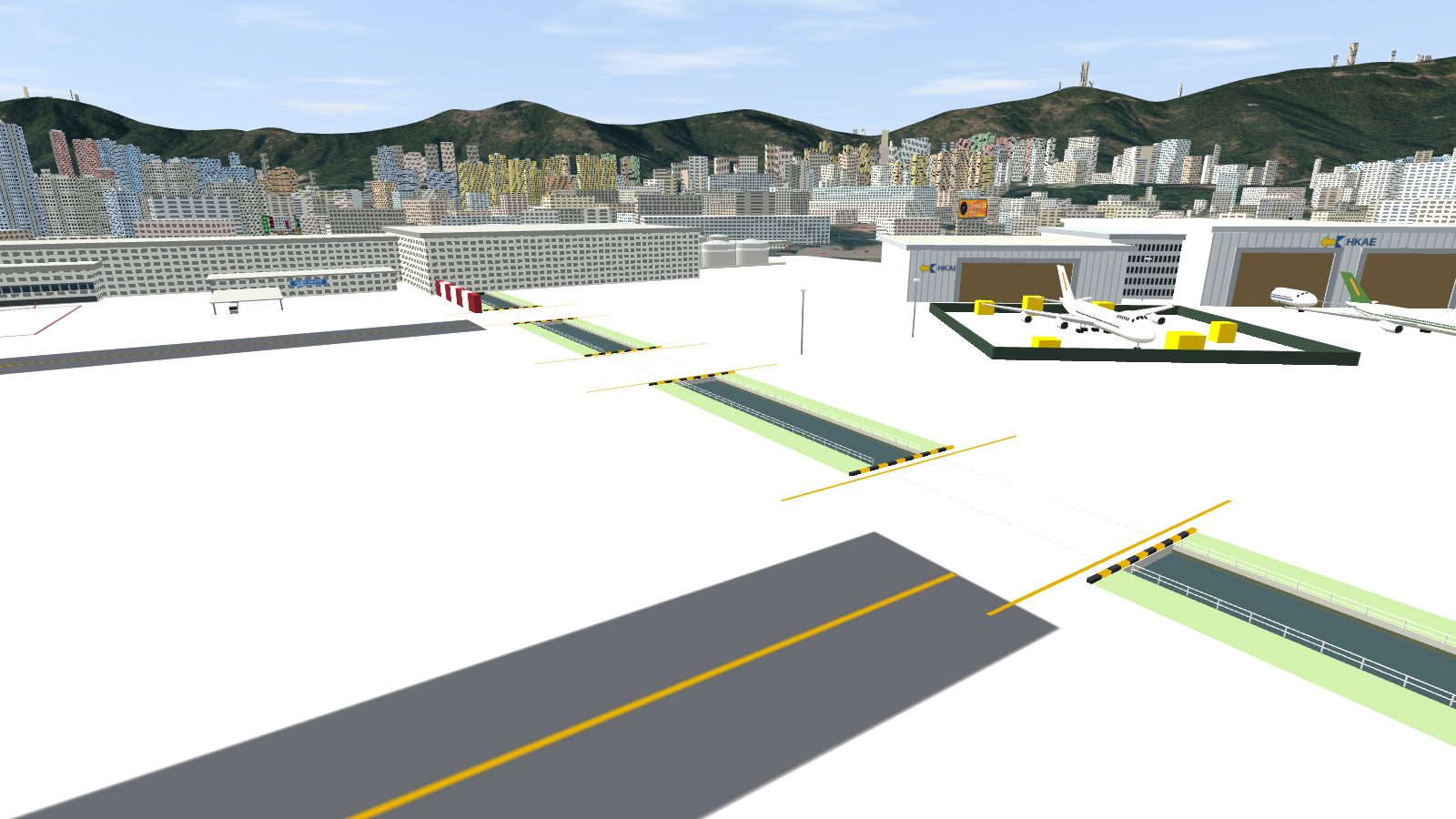 The open channel crossing the apron, with grass verges and railings, broken by taxi bridges with yellow-and-black kerbs, the hangars to the right.