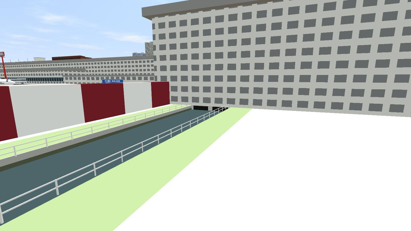 The channel running into dark culvert openings under the north-east end of the terminal, beside the red-and-white blast fence.